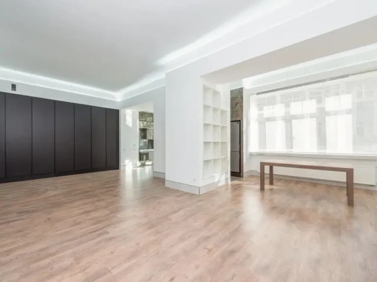 An empty living room with clean floors and daylight