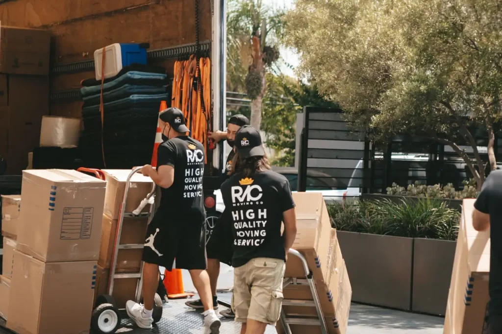 Workers moving boxed items on hand trucks