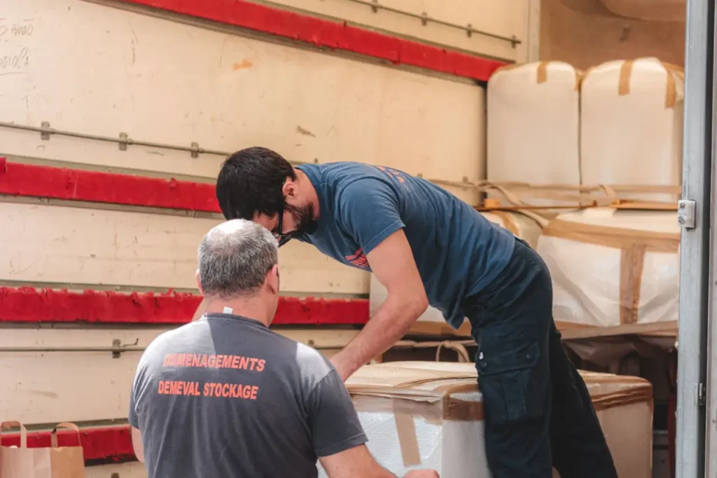 Two workers in uniform unloading items from a vehicle