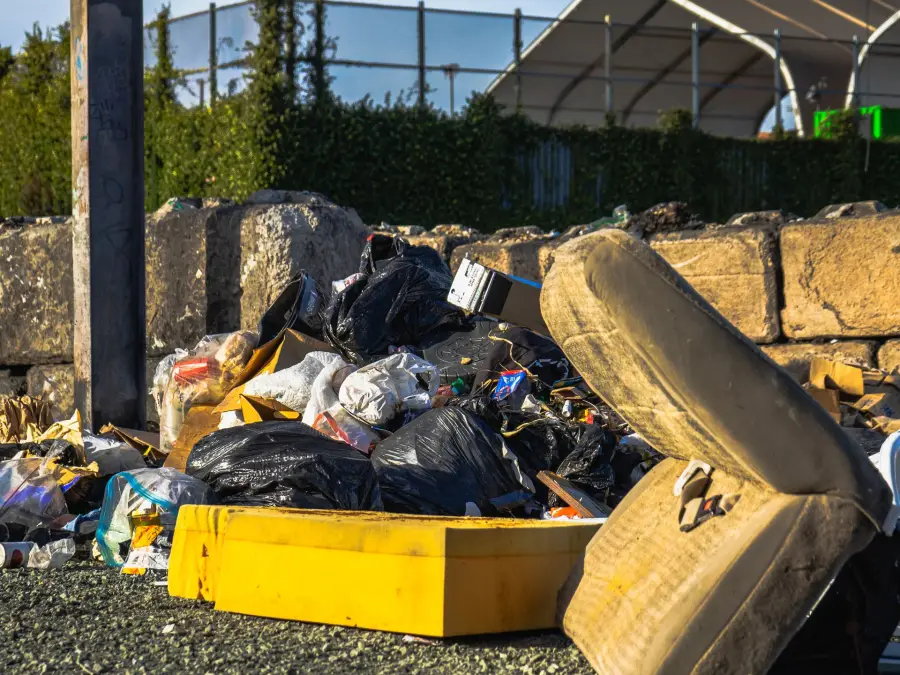 A discarded mattress and household waste stacked outdoors