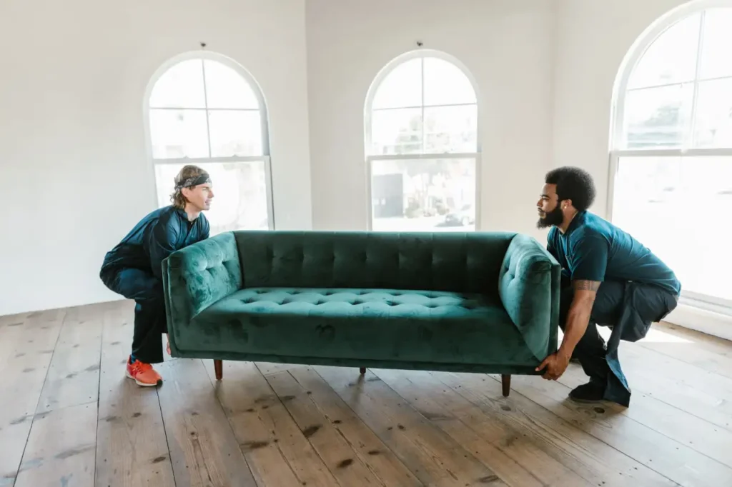 Two people carrying a sofa out of a room